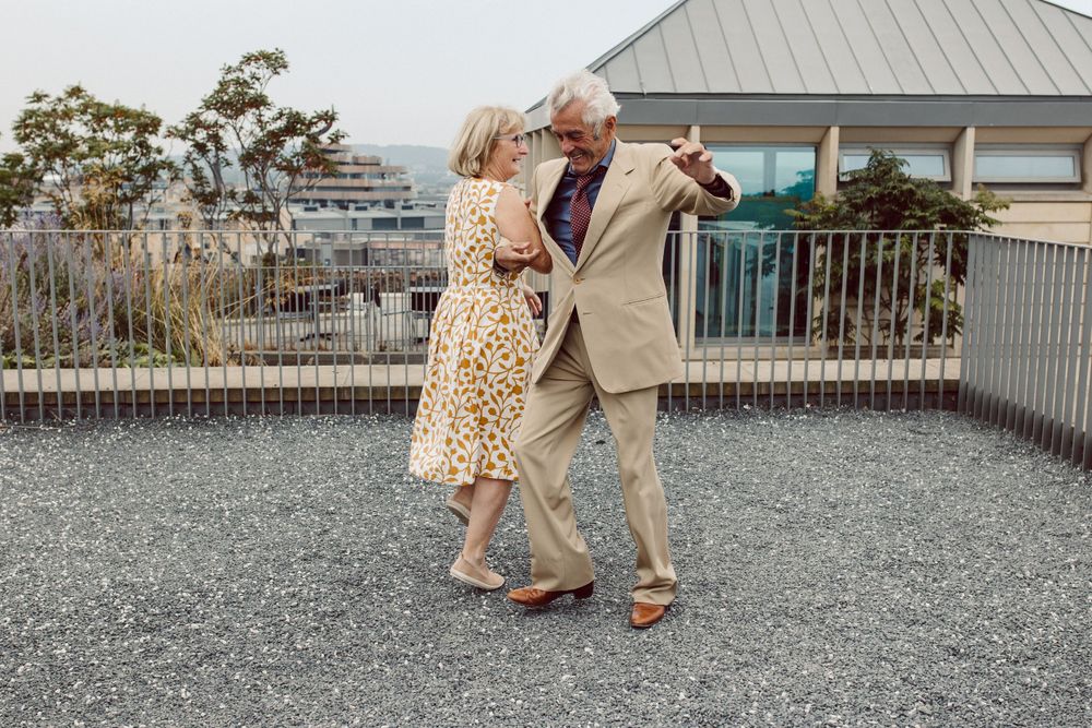 Wedding guests walking and mingling on outdoor gravel terrace.