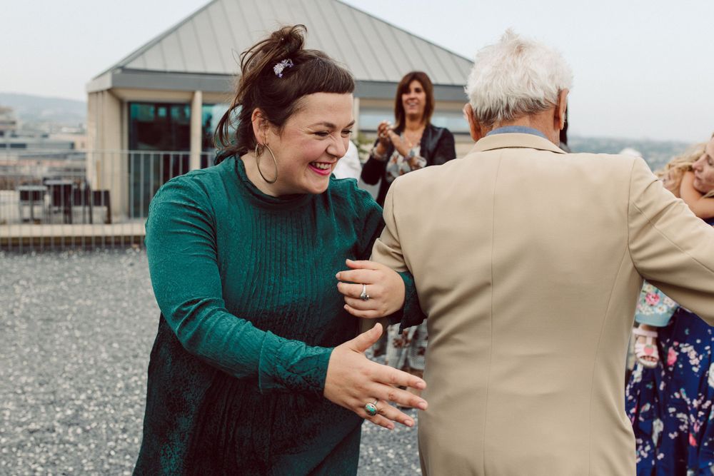 Wedding guests dancing and celebrating together on a rooftop terrace with joyful expressions.