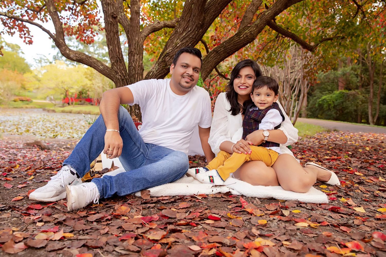 Family portrait on autumn ground with fallen leaves and natural setting.