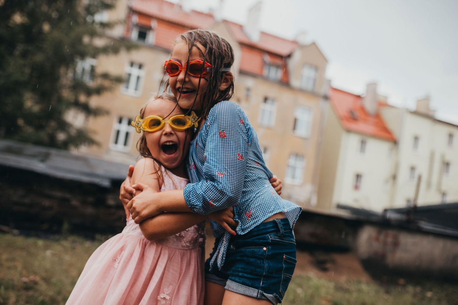 Two people sharing a joyful embrace outdoors near residential buildings.