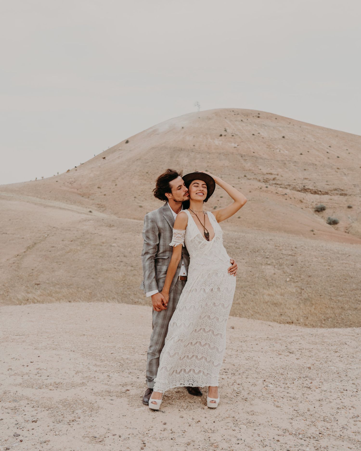Romantic desert wedding photo session with couple against sandy hills.