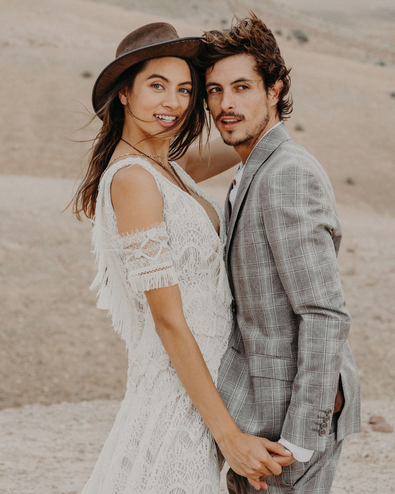 Desert wedding portrait featuring couple in bohemian style attire.