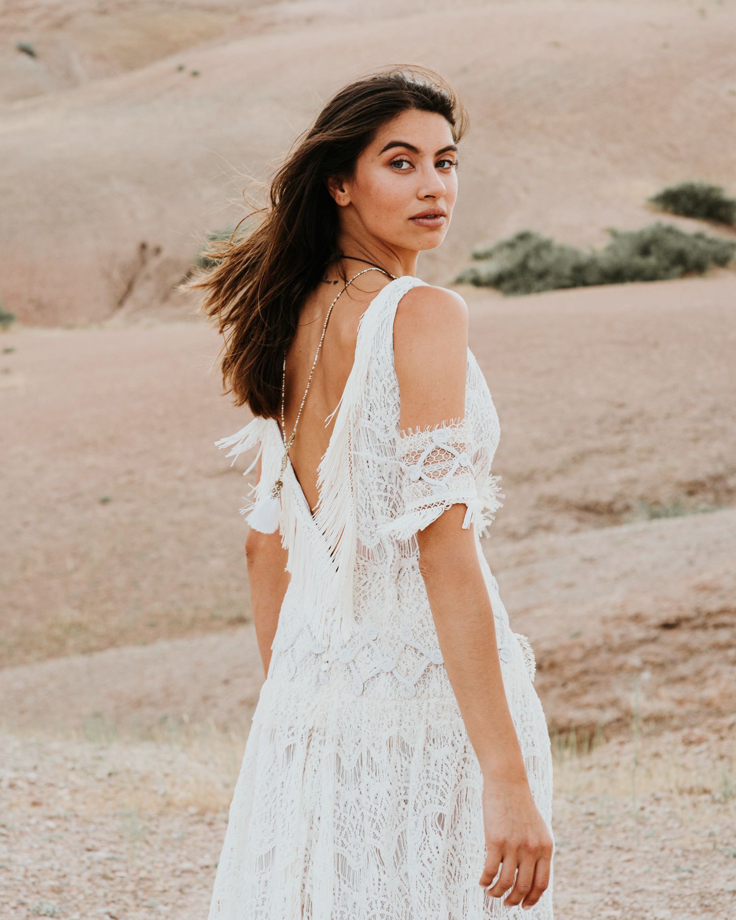 A side profile shot of a white lace dress with desert mountains in background.