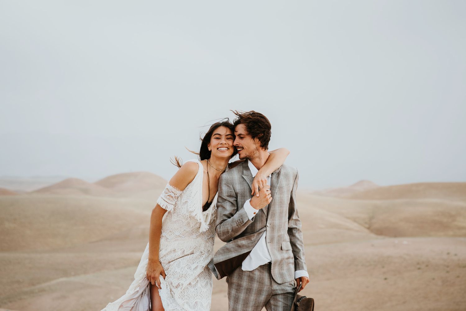 A romantic moment captured between a couple in wedding attire in a desert setting.