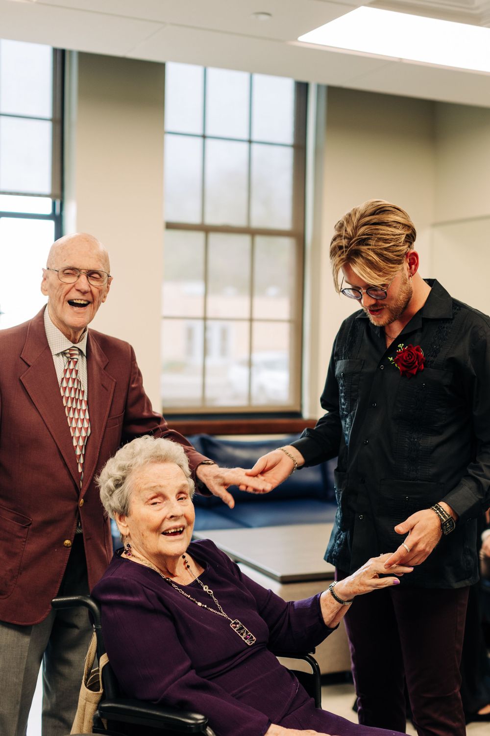 Three people share a joyful moment in a bright indoor space.