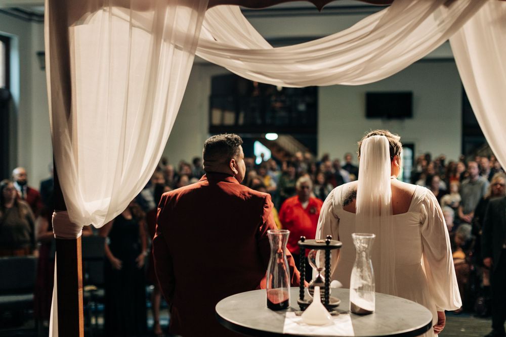 Wedding ceremony altar setting with white draping and wine glasses on a table.