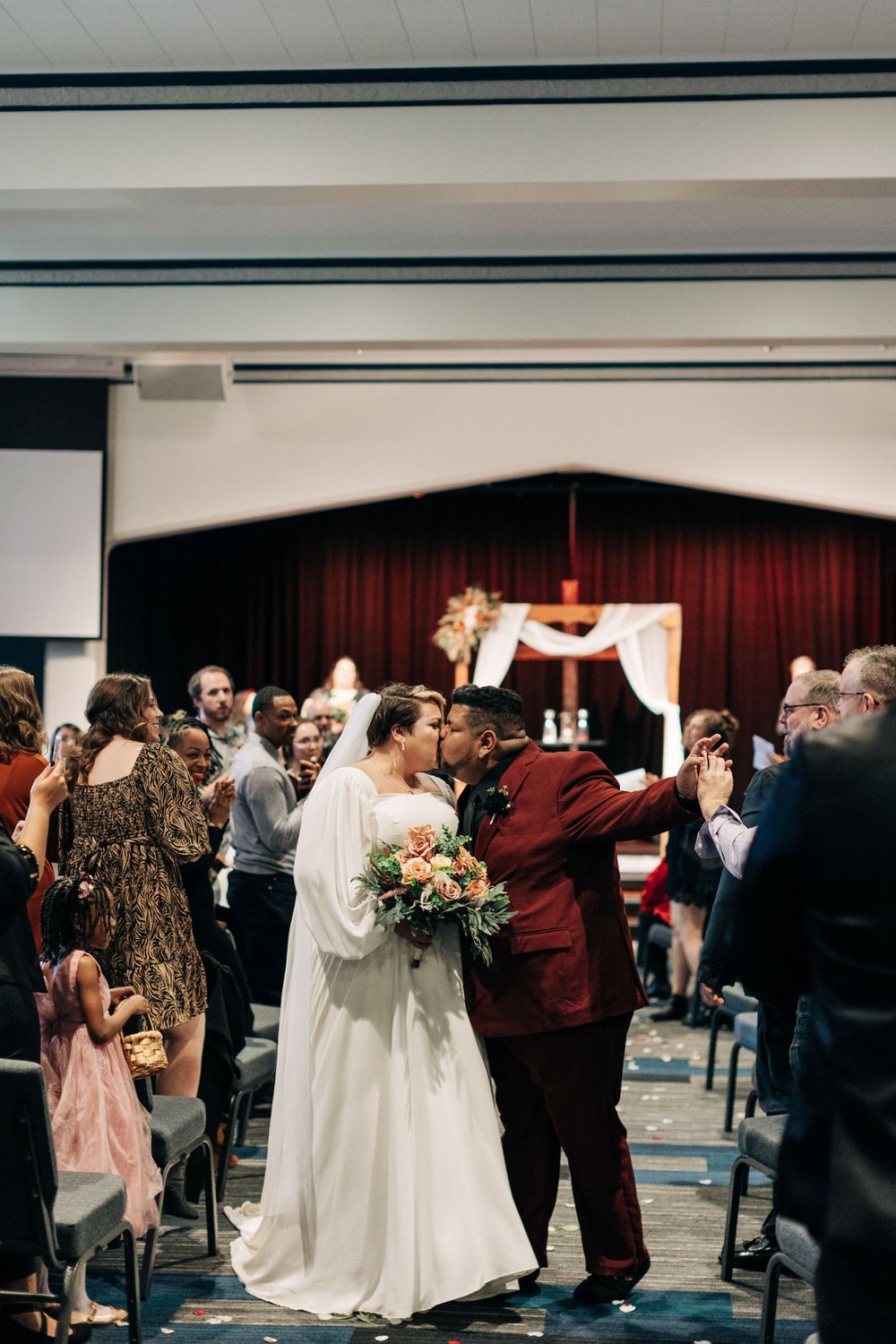 A wedding celebration in a reception hall with guests mingling around the newlyweds.