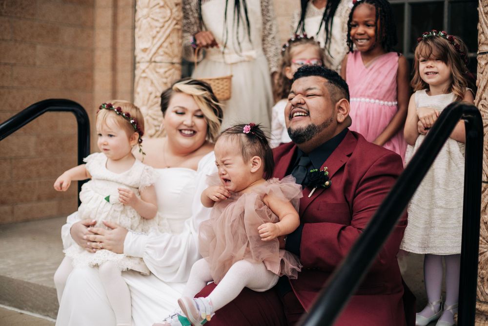 A candid wedding family portrait showing laughter and joy on outdoor steps.
