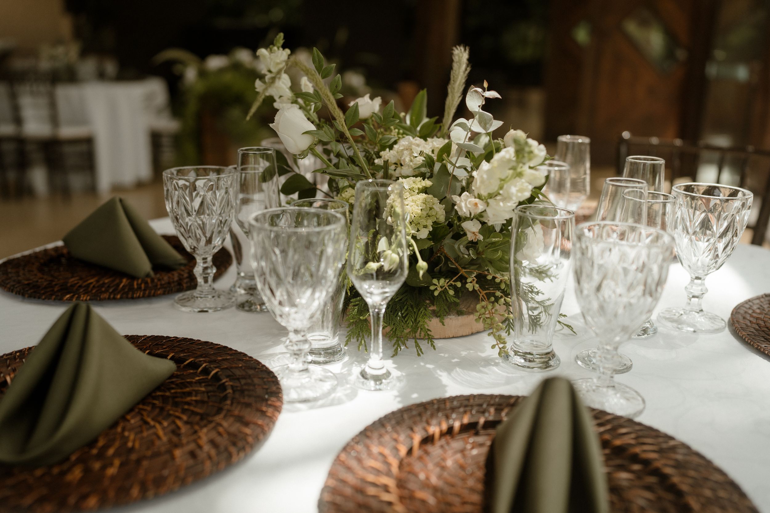 Elegant wedding reception table setting with white floral arrangements and glassware.