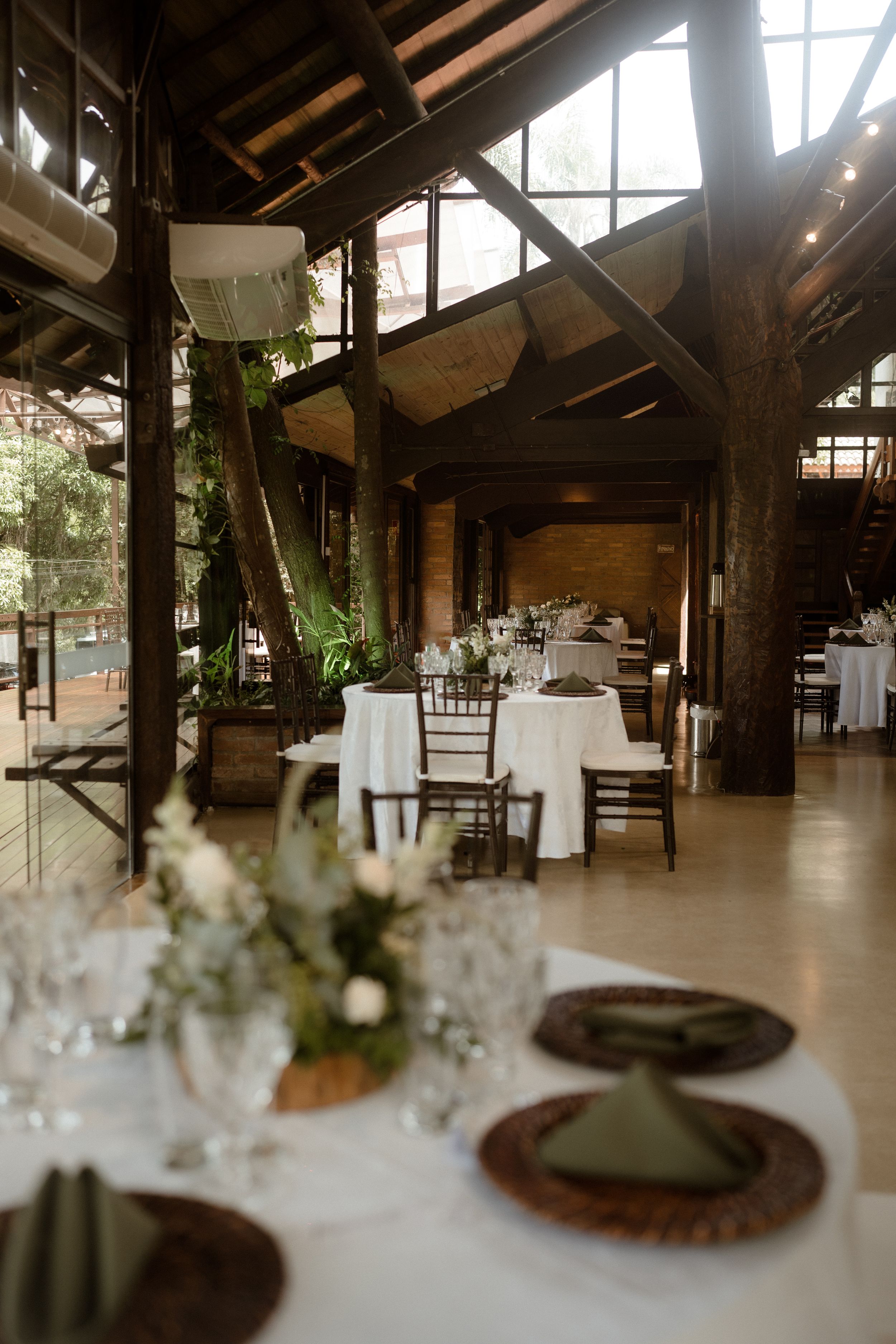 Rustic wooden event venue interior with white tablecloths and elegant table settings in a barn-style space.