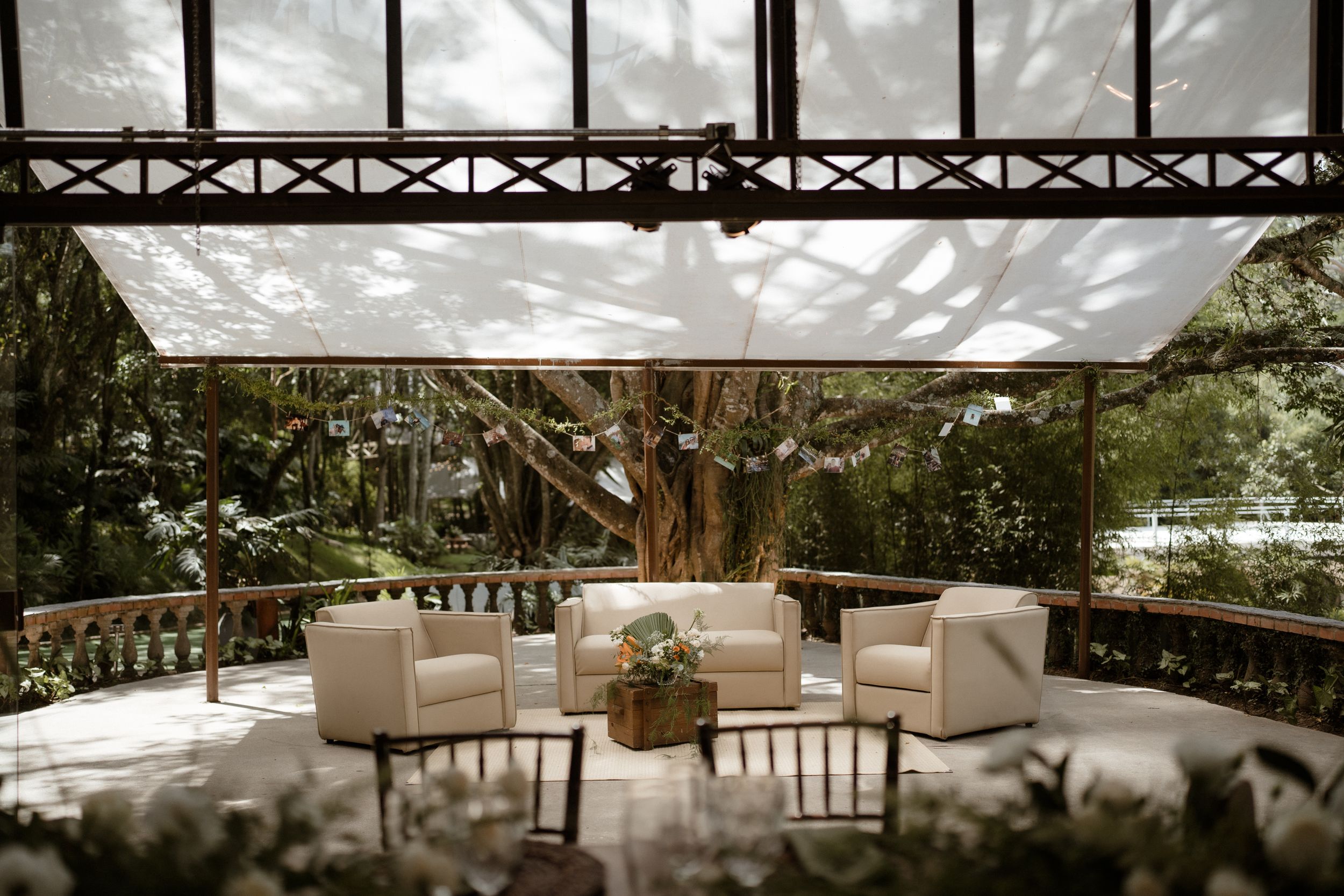 Modern outdoor lounge area with cream chairs and coffee table under a shaded pergola.