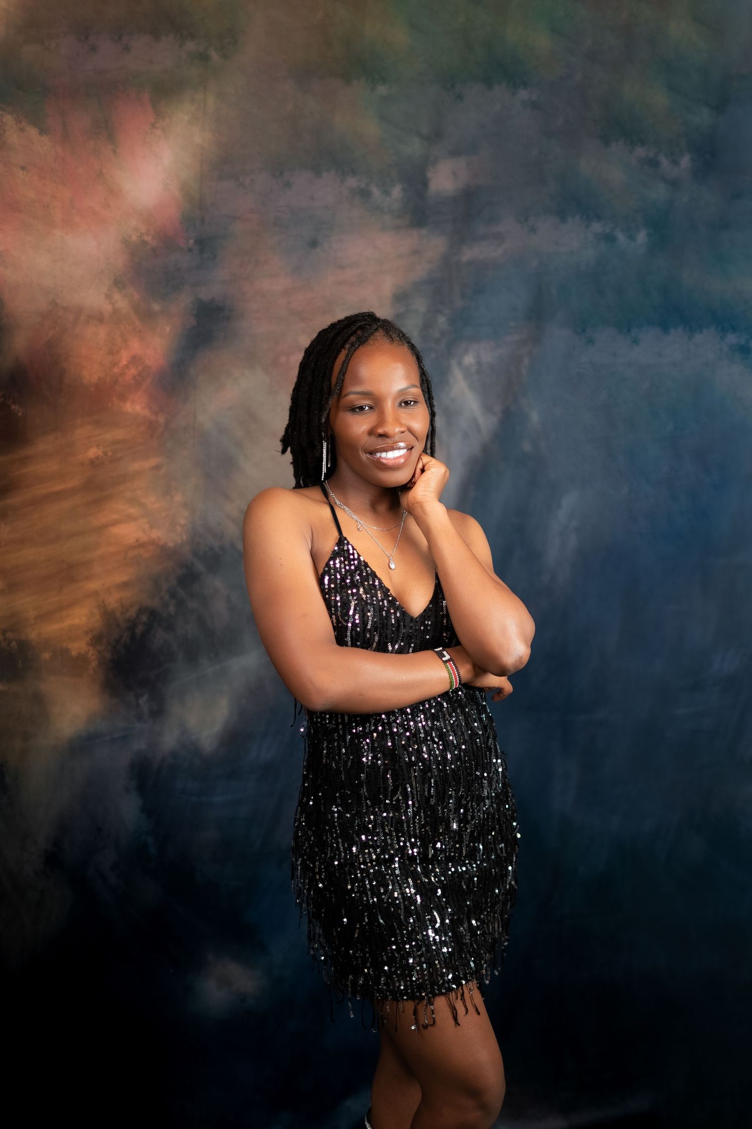 Artistic portrait featuring model in sequined dress against colorful smoky background.