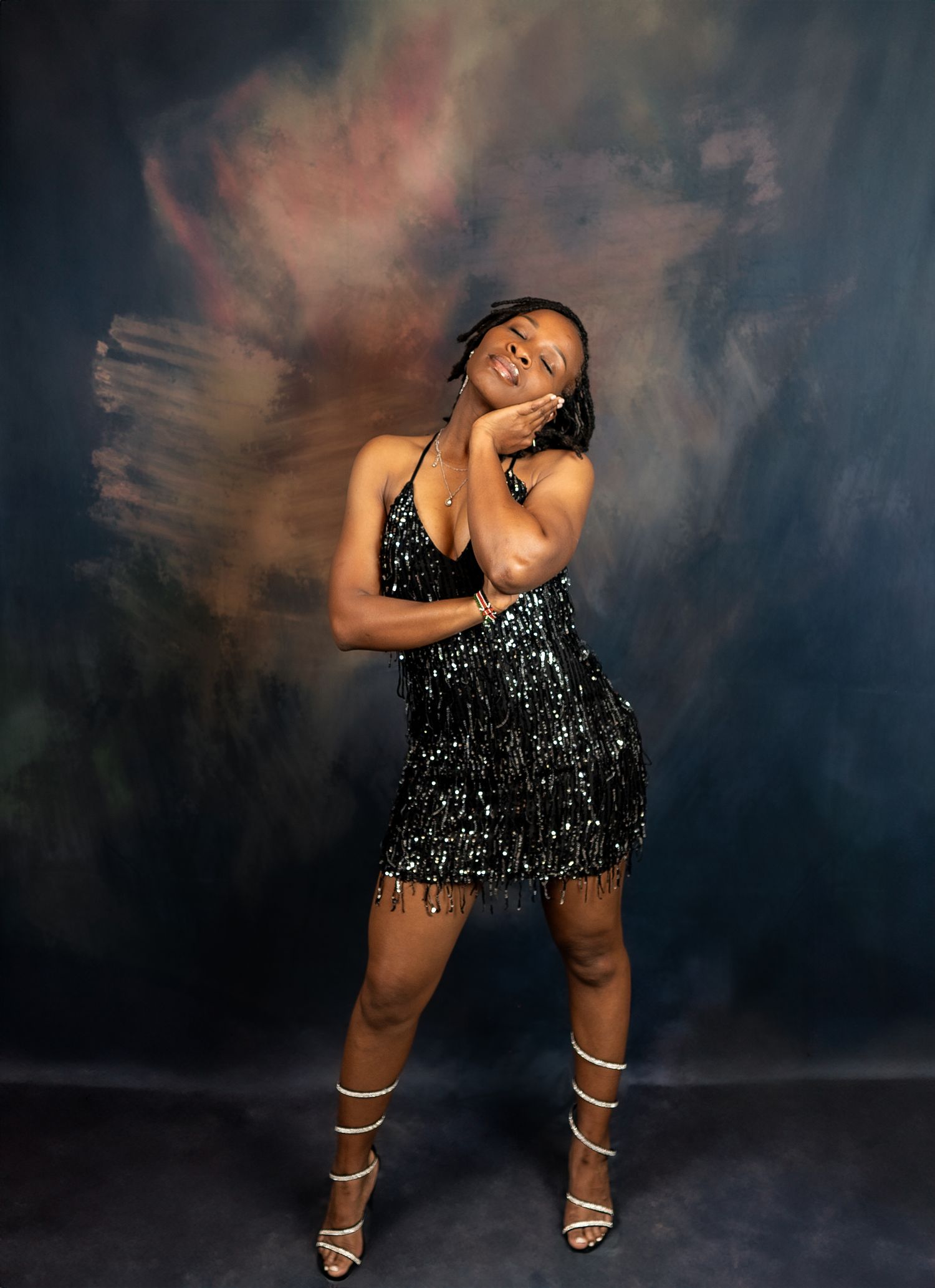 Dynamic dance-inspired pose in sparkling black cocktail dress.