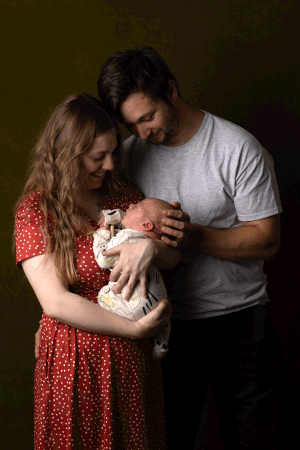 Beautiful family smiling down at baby during an in-home newborn session in Ceredigion
