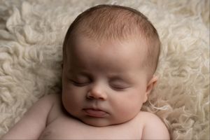 Newborn sleeping peacefully on a cream flokati blanket with Ceredigion newborn photographer
