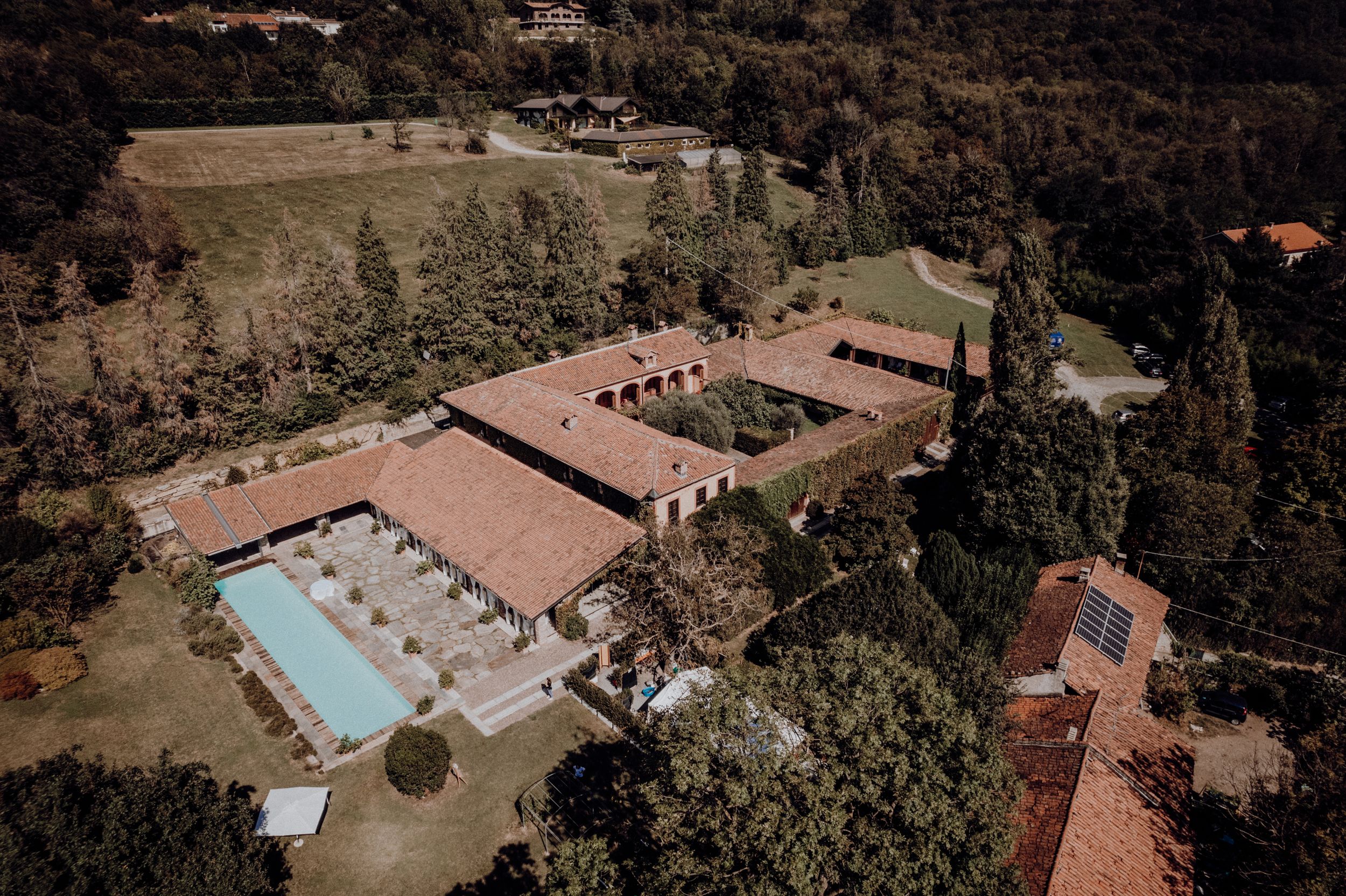 Aerial view of Italian wedding venue estate with pool surrounded by cypress trees.