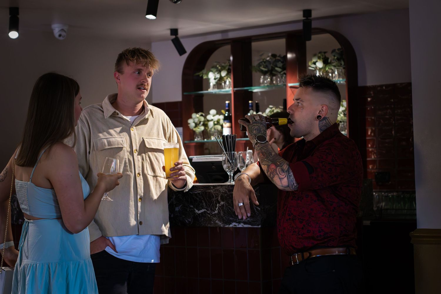 People gathered in conversation at a dimly lit bar or social venue.