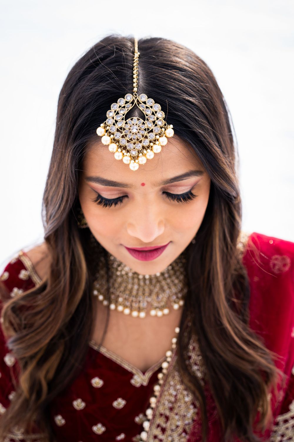 Close-up of traditional Indian bridal jewelry featuring an ornate tikka headpiece and choker necklace.