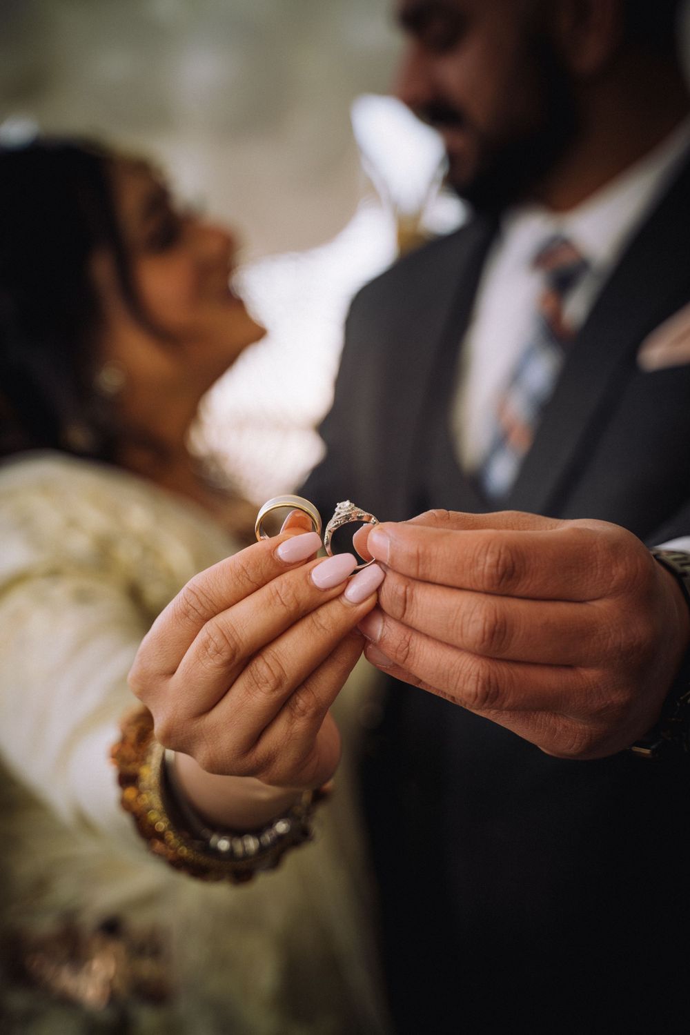 Close-up shot of hands holding wedding rings during an intimate ceremony moment.