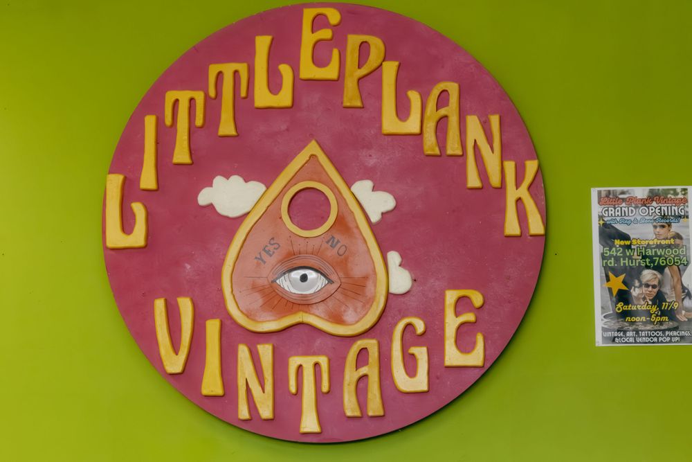 Vintage-style circular sign reading 'Little Plank Vintage' with mystic eye symbol on lime green wall.