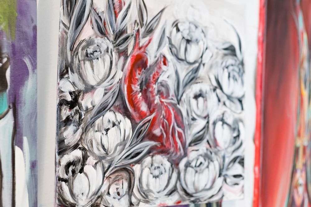 Painting of a red anatomical heart surrounded by gray and white flowers on a textured canvas background.