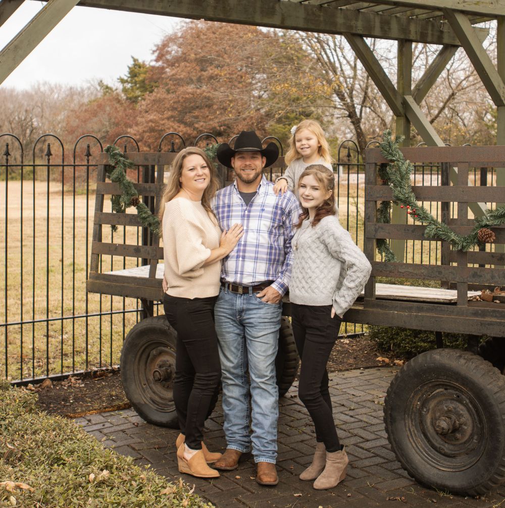 Family group poses together on a rustic wagon in an autumn setting.