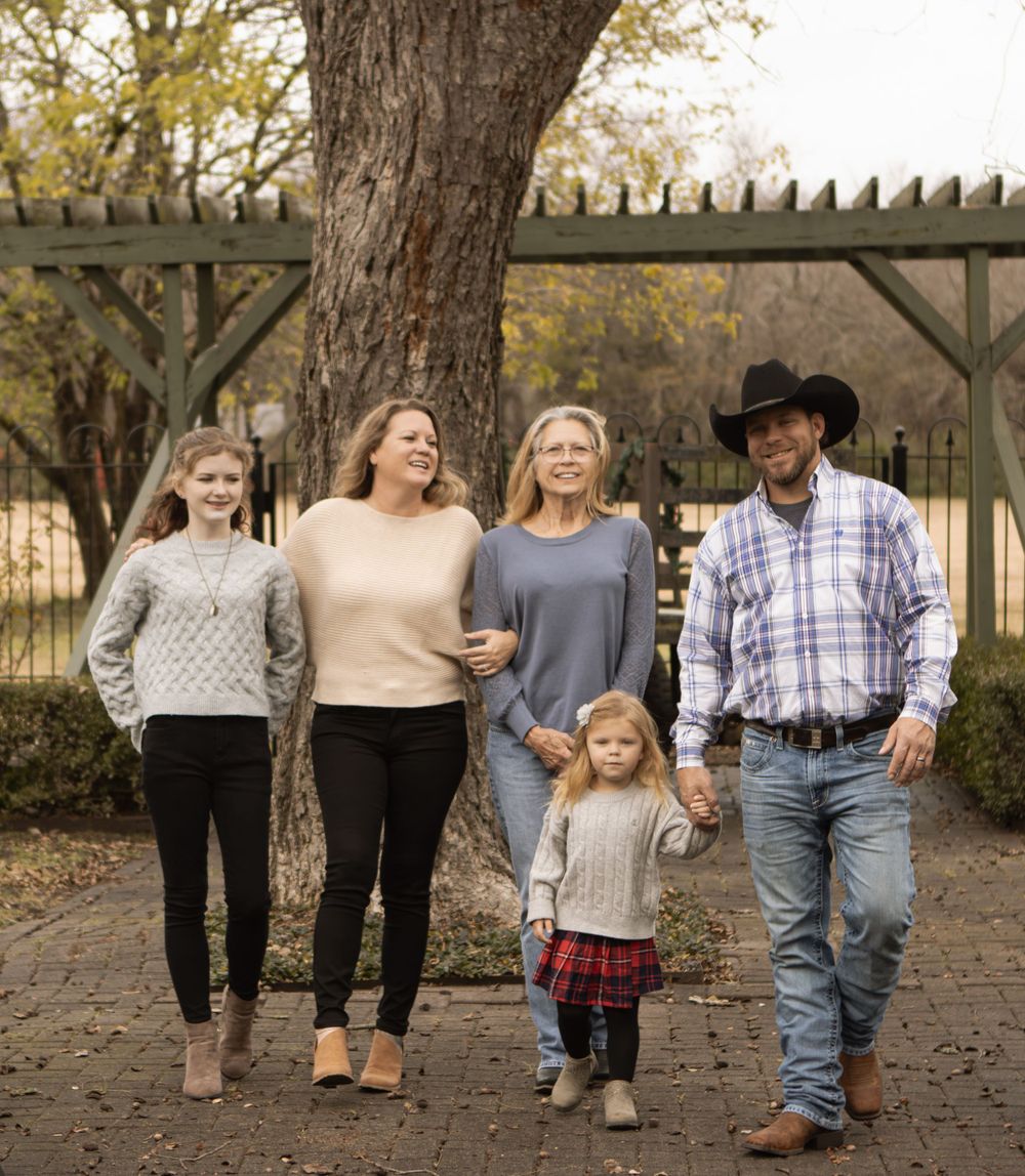 Family walking together on a path under autumn trees.