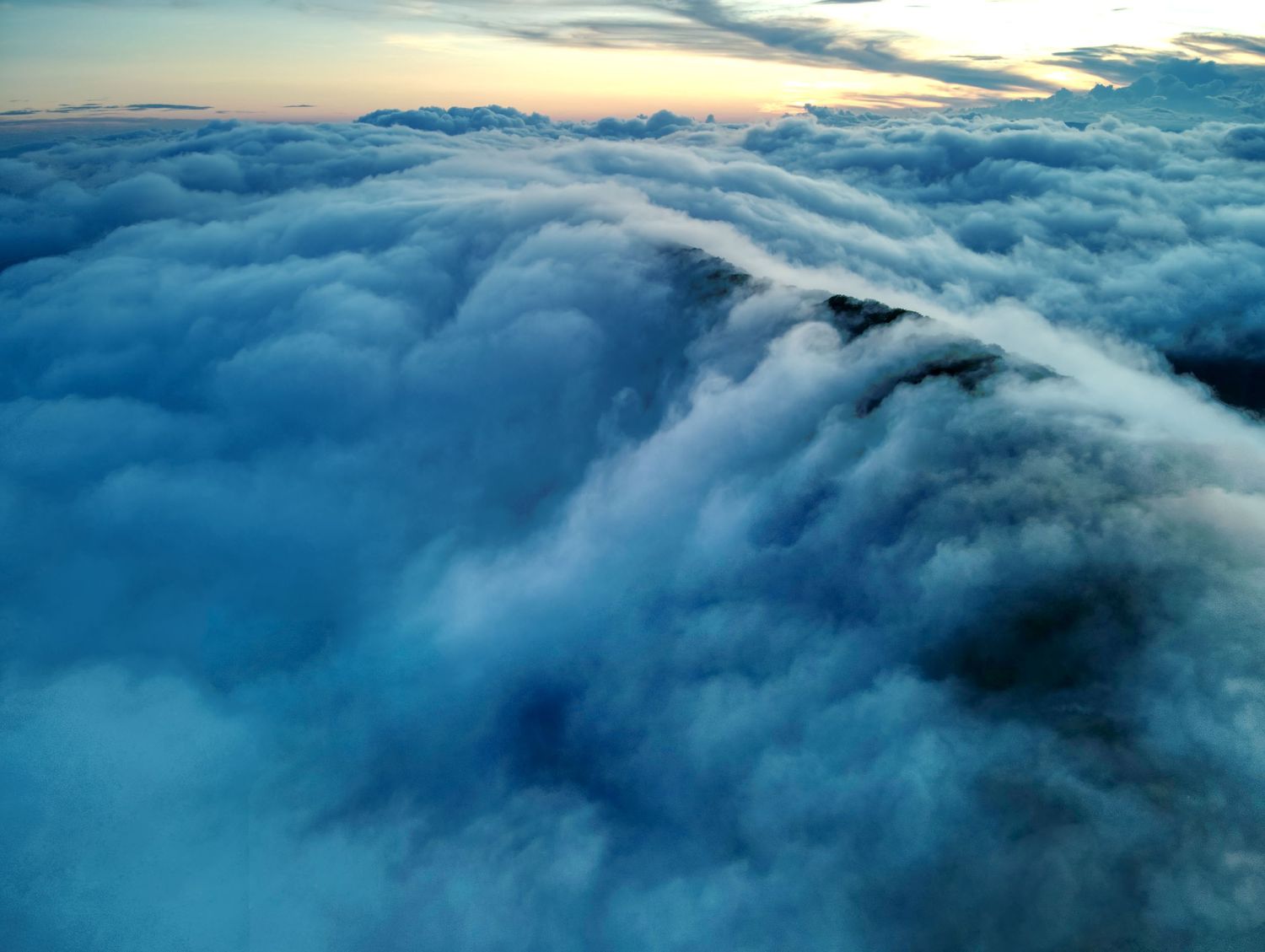 A beautiful golden sunset above the clouds of a mountain range.