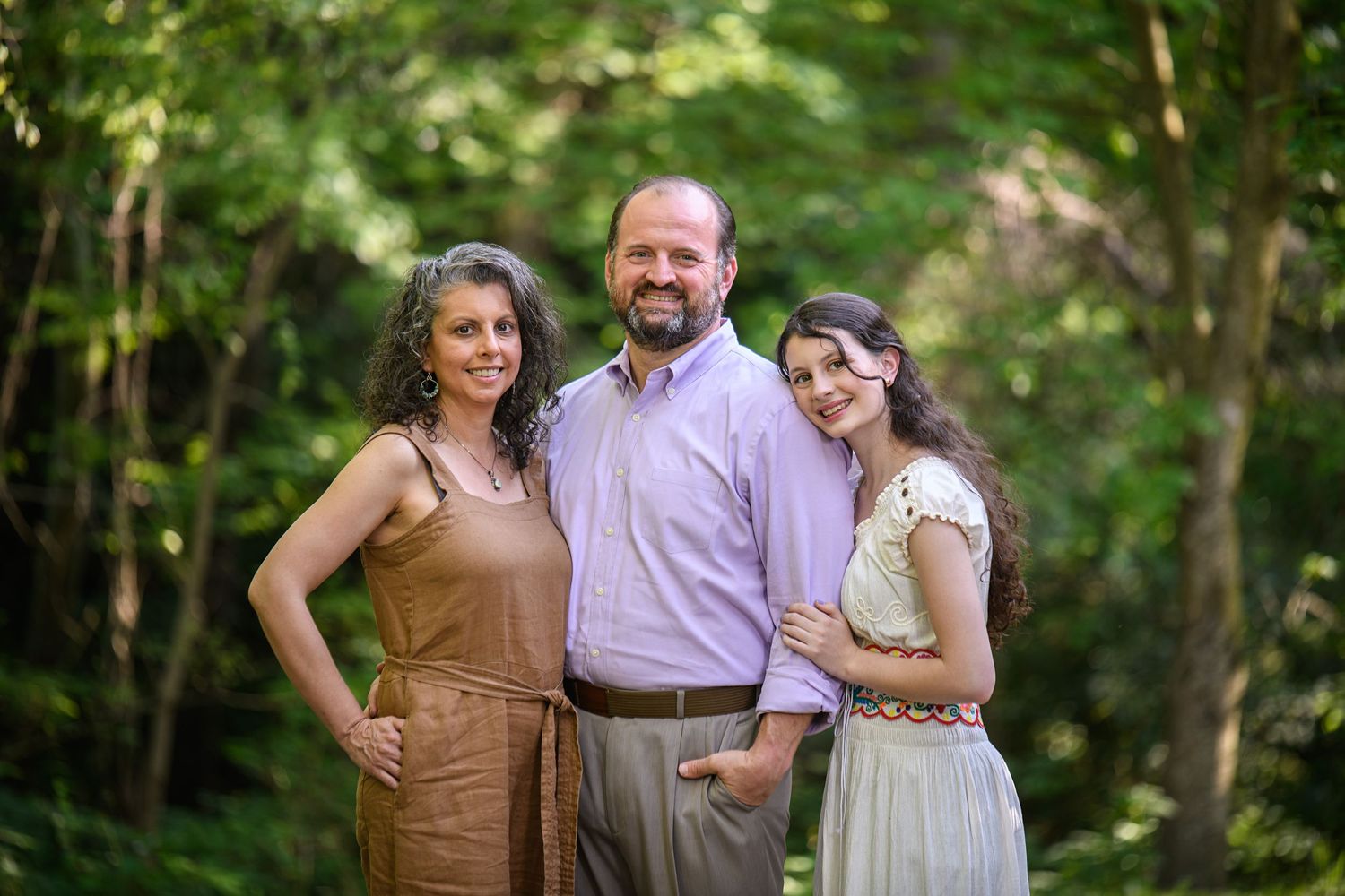 Family portrait session in a lush green forest setting during golden hour.