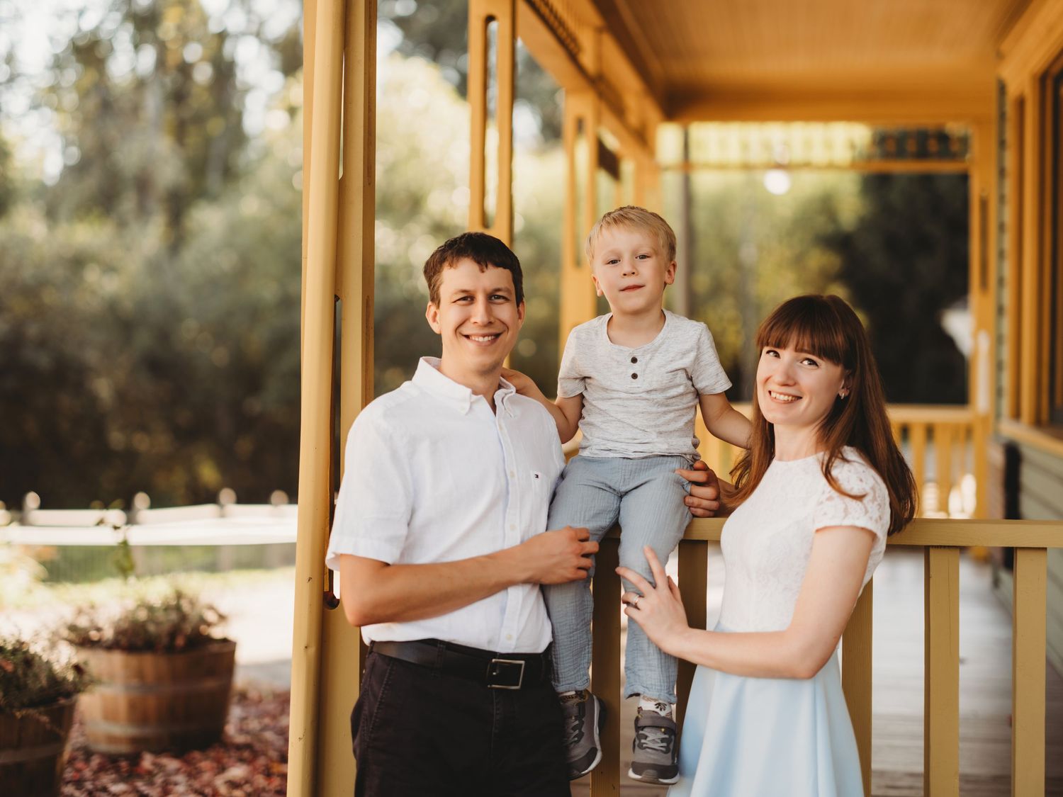 A family photo on a covered porch with potted plants in warm lighting.