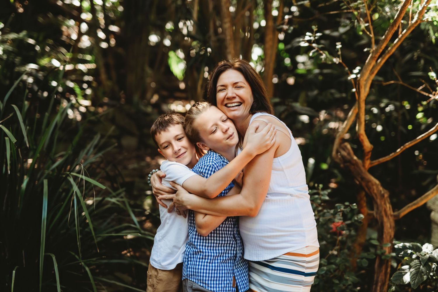 A joyful group hug shared outdoors in a lush green garden setting.