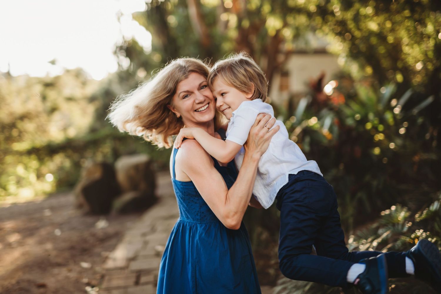 Tender embrace shared between two people in a sunlit garden setting.
