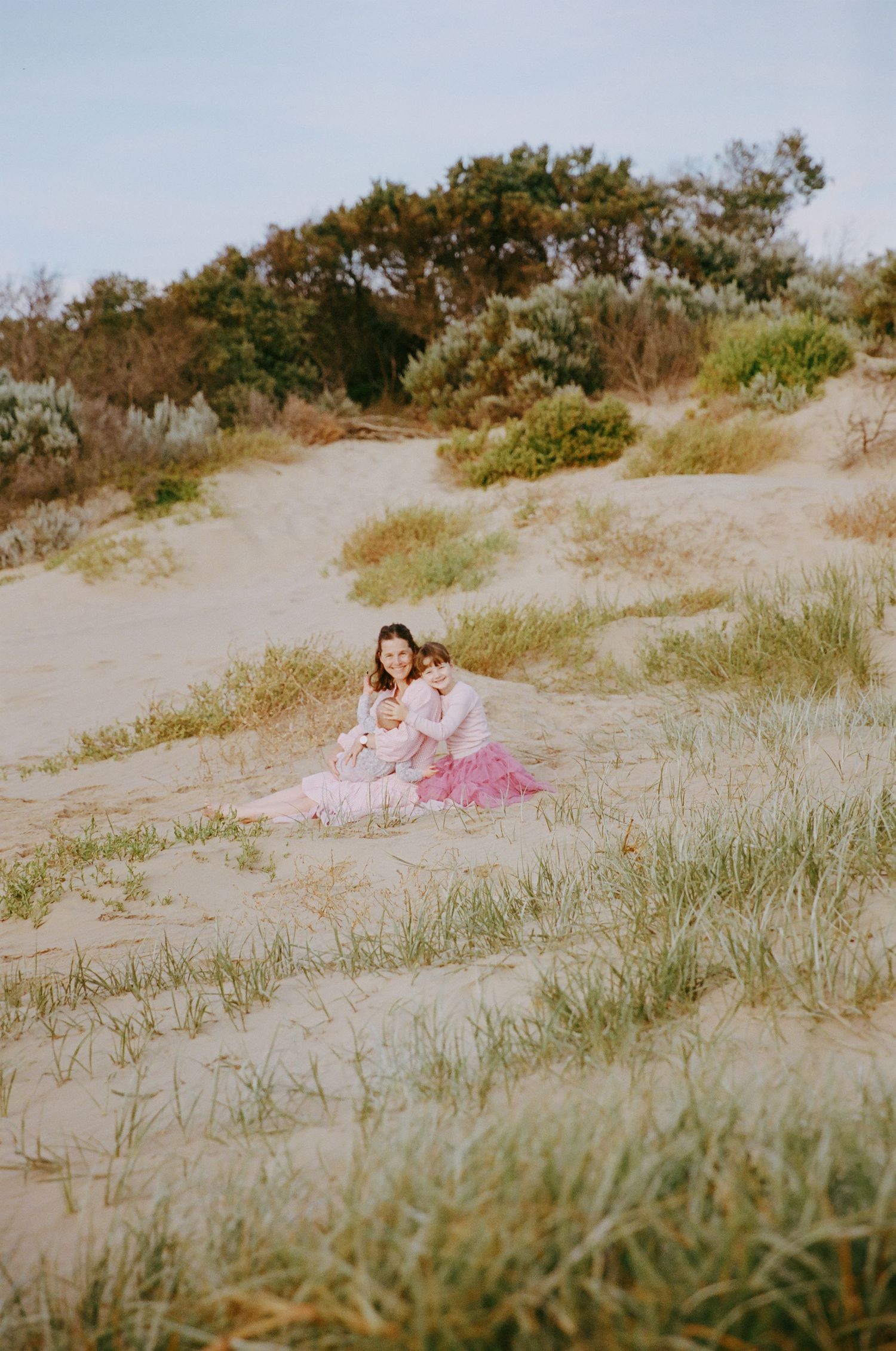 Mother and children snuggling in the sand dunes in Ocean Grove