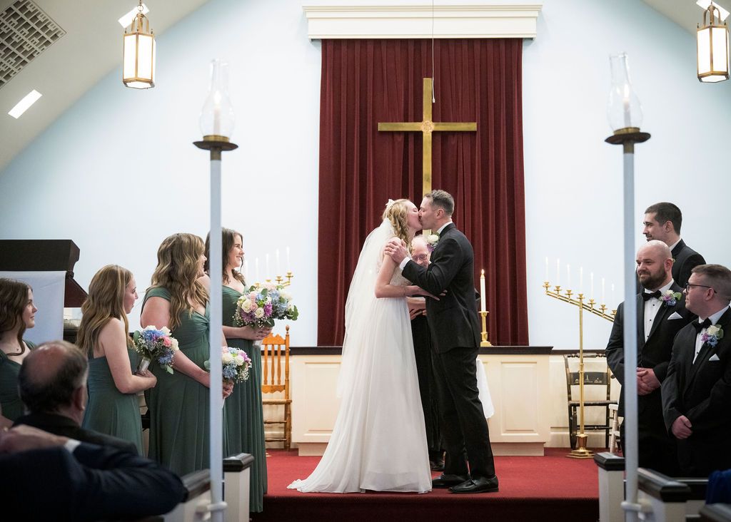 Wedding ceremony sequence in church with white cross and burgundy curtains as backdrop.