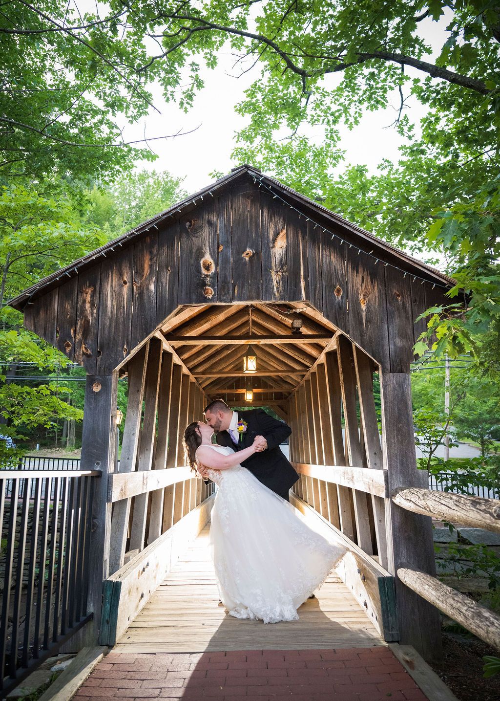 A romantic wedding photo sequence on a wooden covered bridge decorated with string lights.
