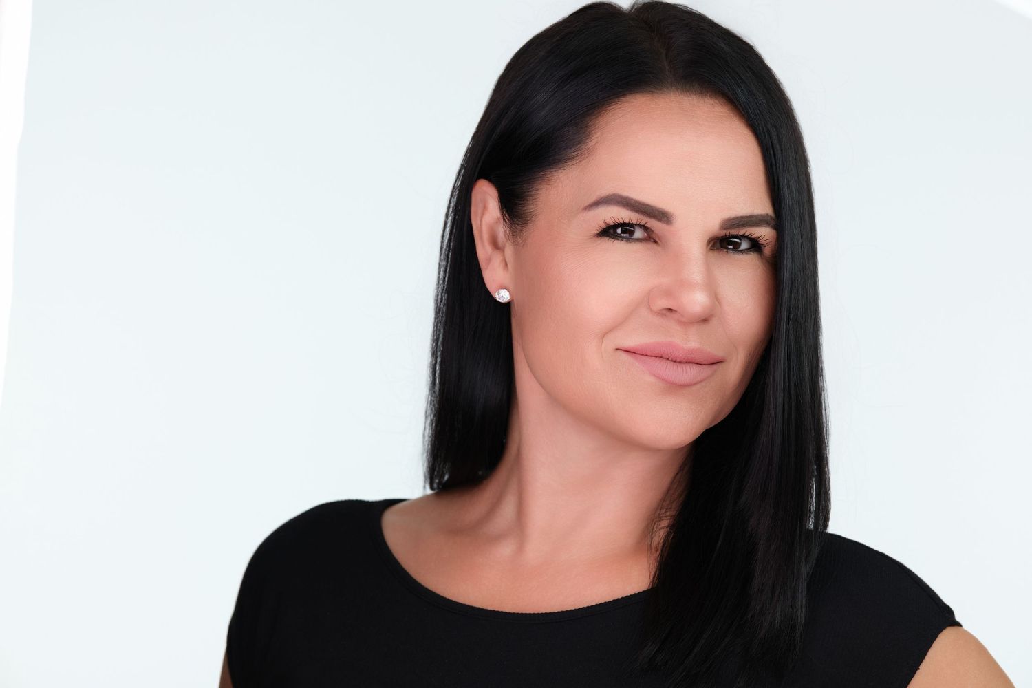 Professional headshot photo of a woman with long dark hair smiling against a white background.