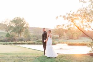 Romantic sunset wedding portrait overlooking peaceful lake and rolling hills.
