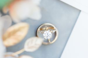 A sparkling diamond engagement ring photographed in soft focus with a blurred background.