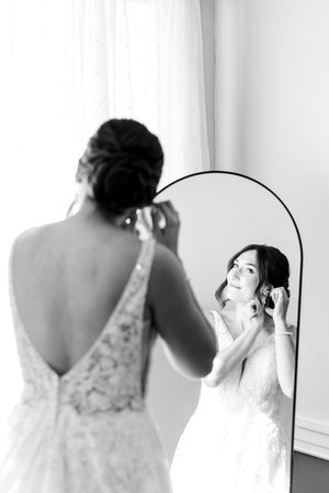 A series of black and white photos showing a bride getting ready in front of a mirror wearing a lace wedding dress.