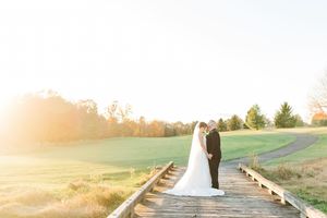 Couple walks together on a sunlit path through rolling green hills during golden hour wedding photography session.