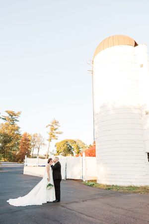 A bride and groom pose for romantic portraits against white architectural walls during golden hour.