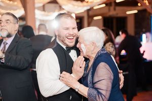 Wedding reception guests dancing and celebrating on a dimly lit dance floor with warm lighting.