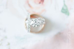 Close-up of stunning diamond engagement ring with intricate details on soft pink background.