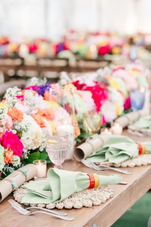 Elegant table setting with vibrant floral centerpieces and mint green napkins on lace placemats.