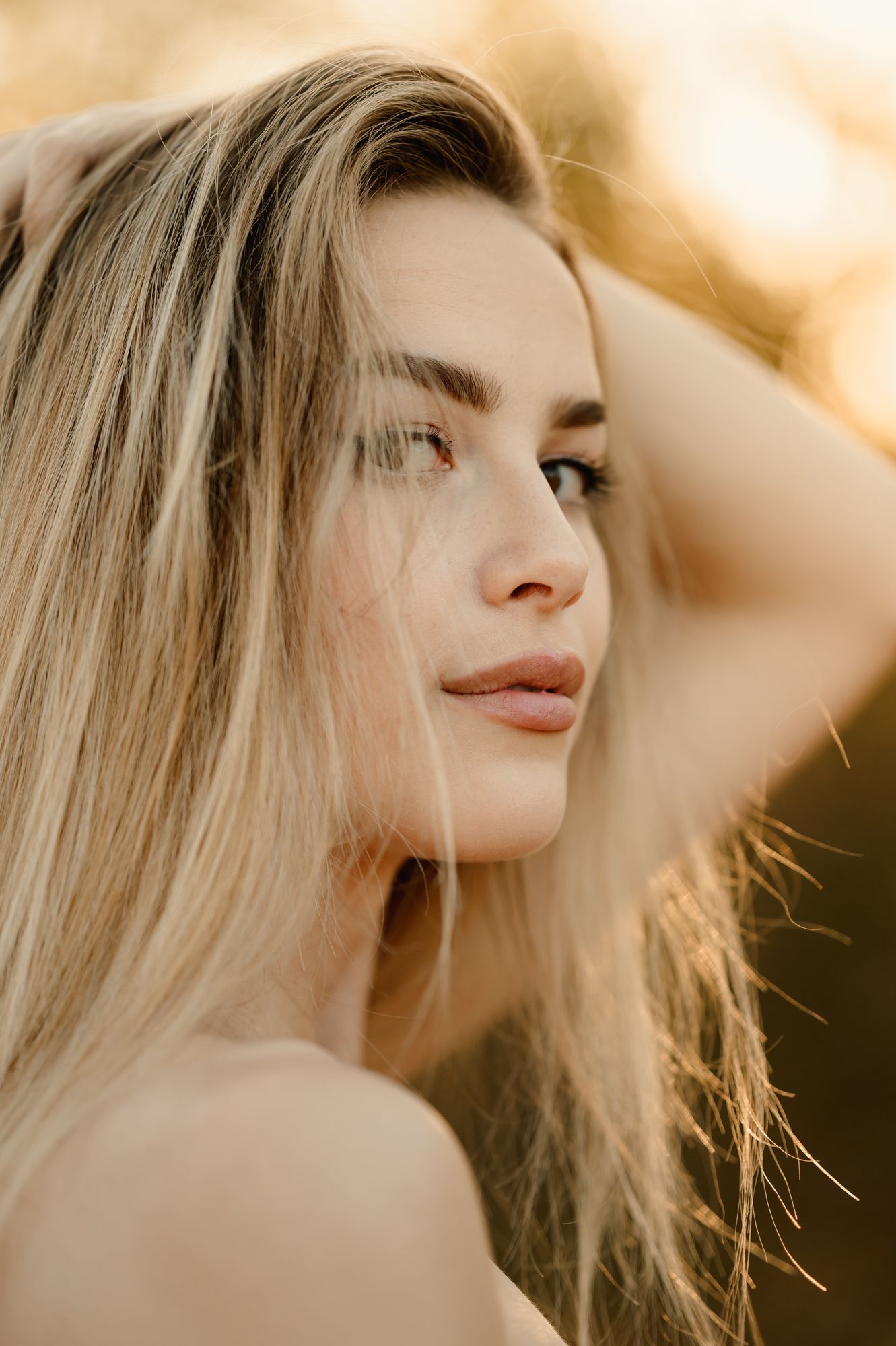 Ojai high school senior photoshoot at golden field by Ventura portrait photographer, of girl flipping her hair in golden sunlight