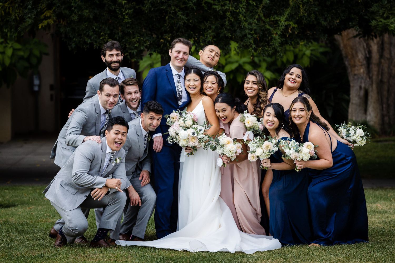 A wedding group photo with the bride, groom, groomsmen, and bridesmaids all smiling joyfully