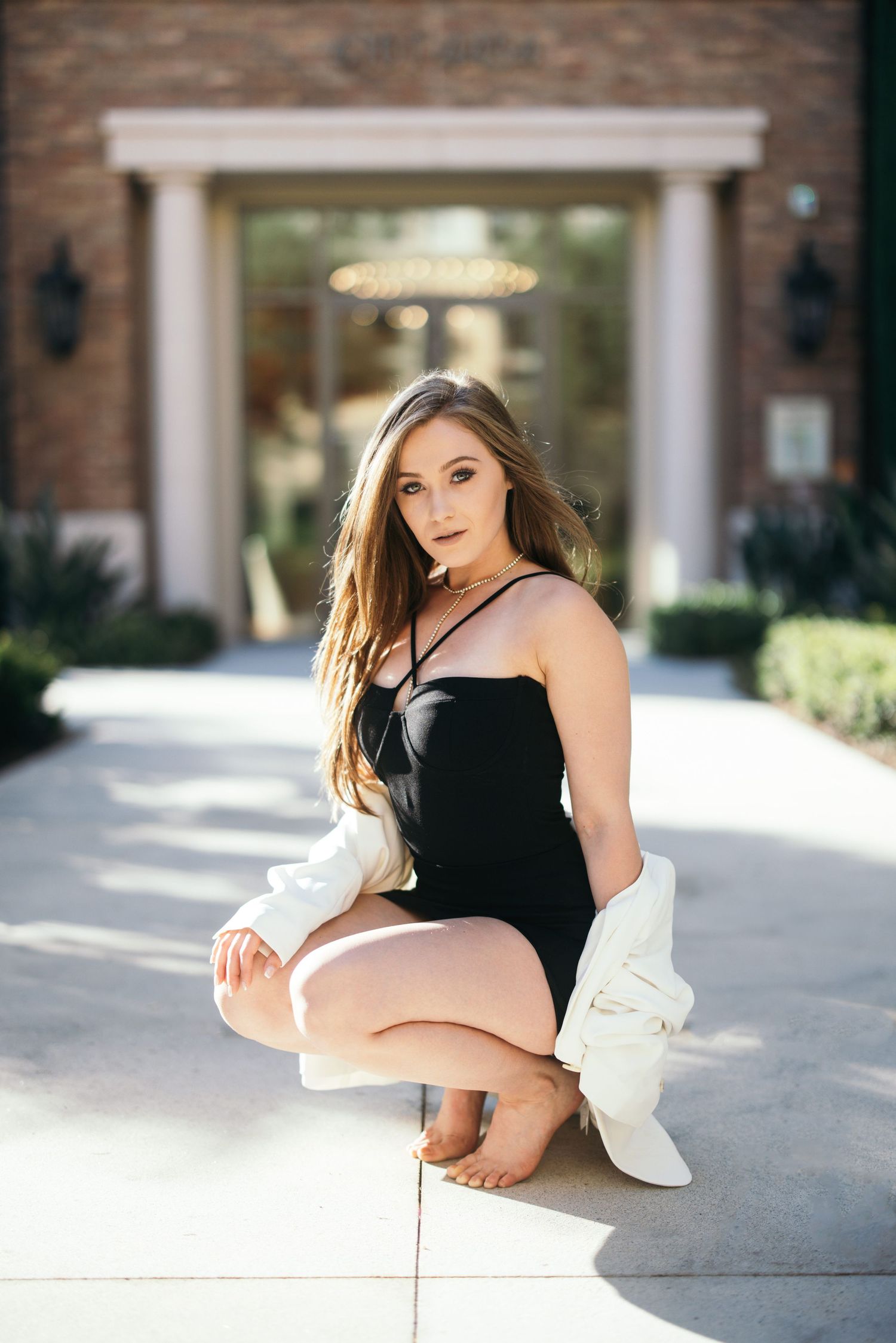 Fashion portrait of woman in black outfit posing in front of elegant building entrance.