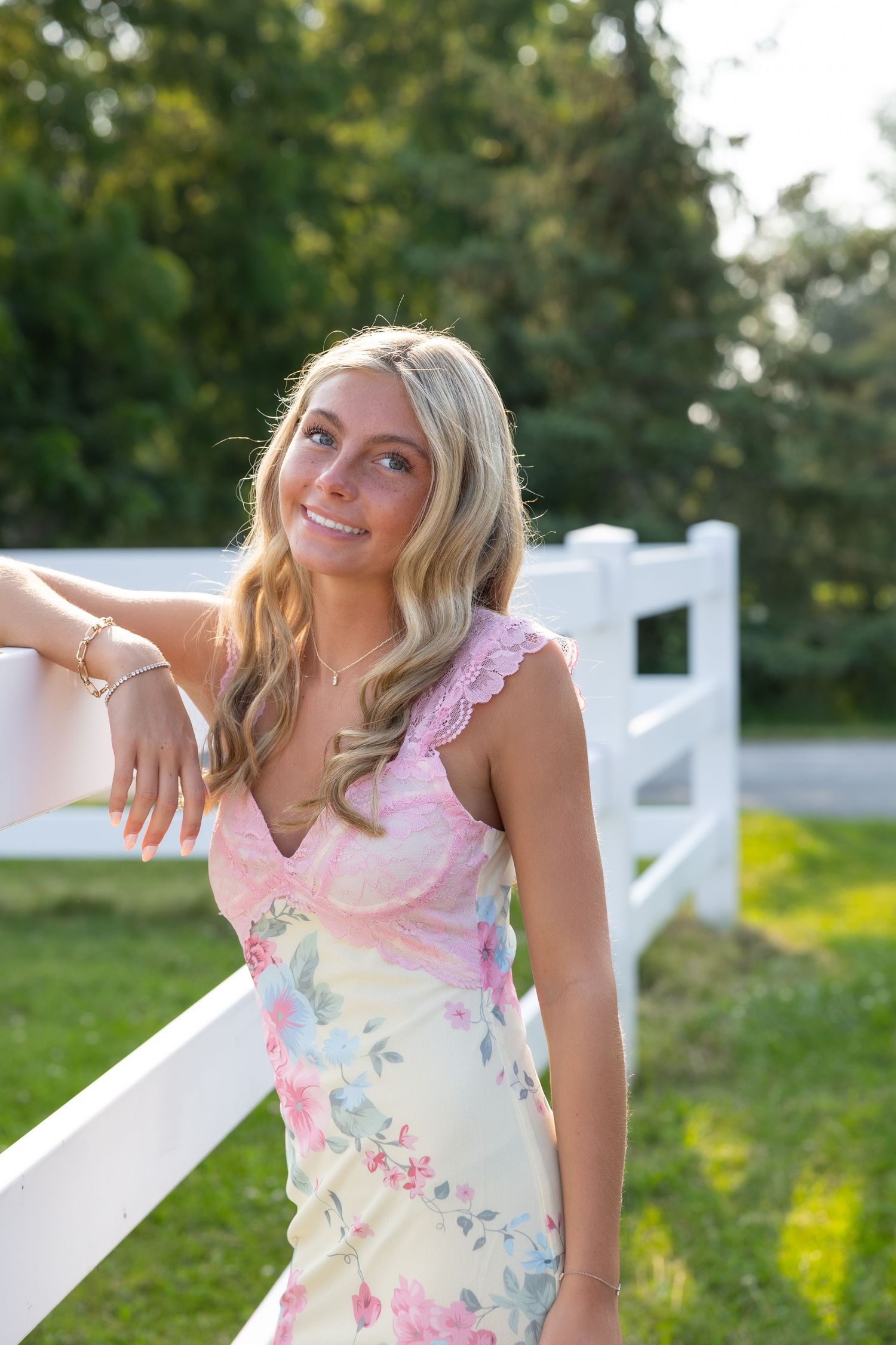 Young woman in white top poses in garden with colorful flowers.