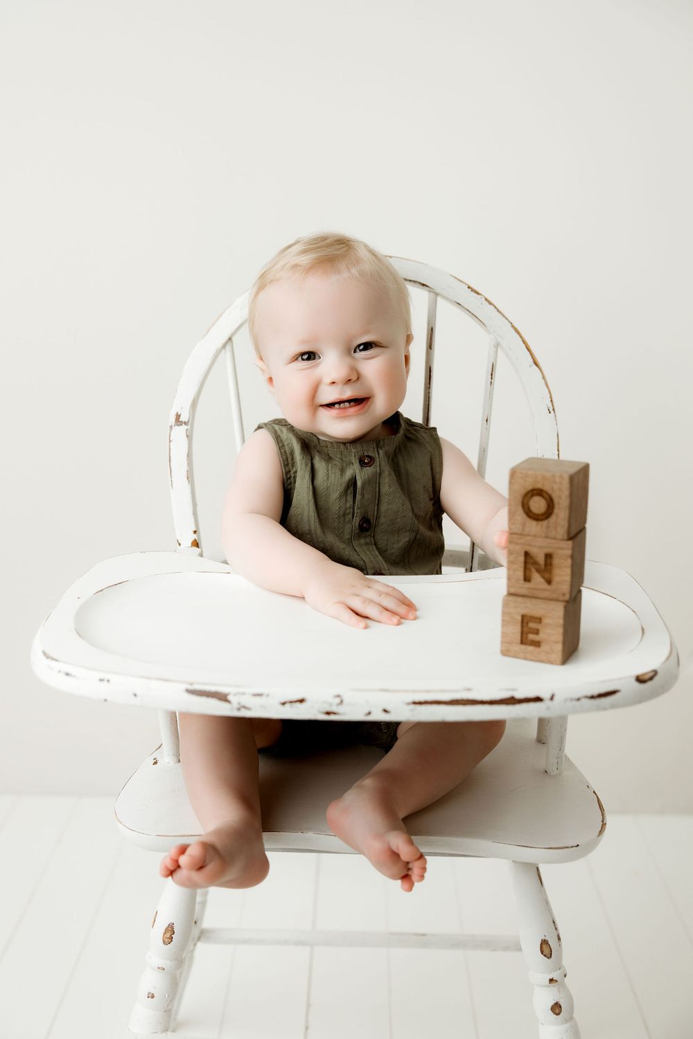 Baby boy sitting In a white vintage high chair playing with baby blocks