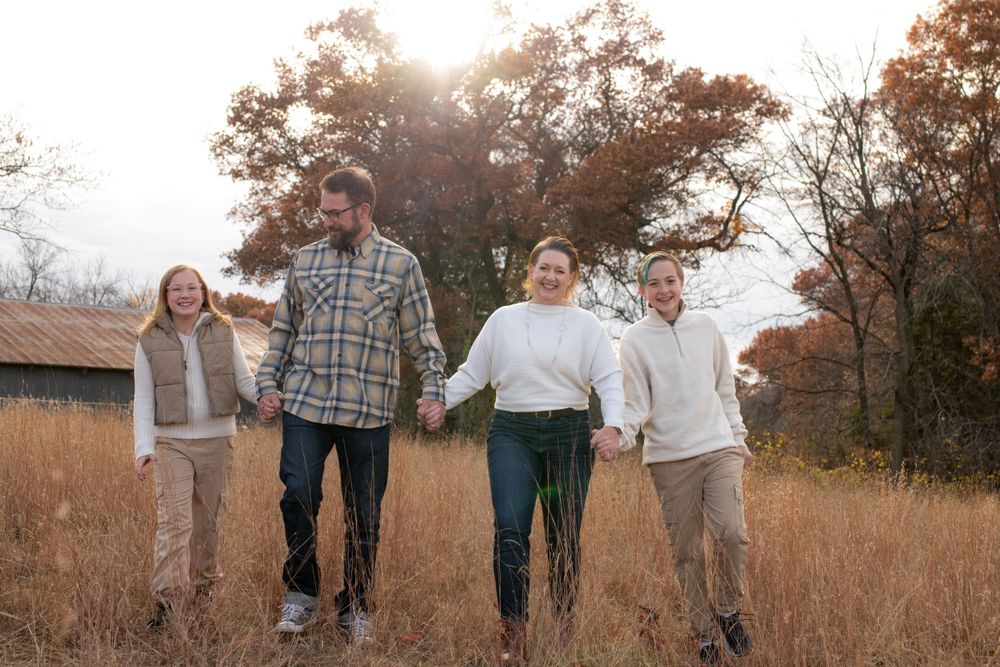A fall family photo session, walking through a golden autumn field with tall grass at sunset.